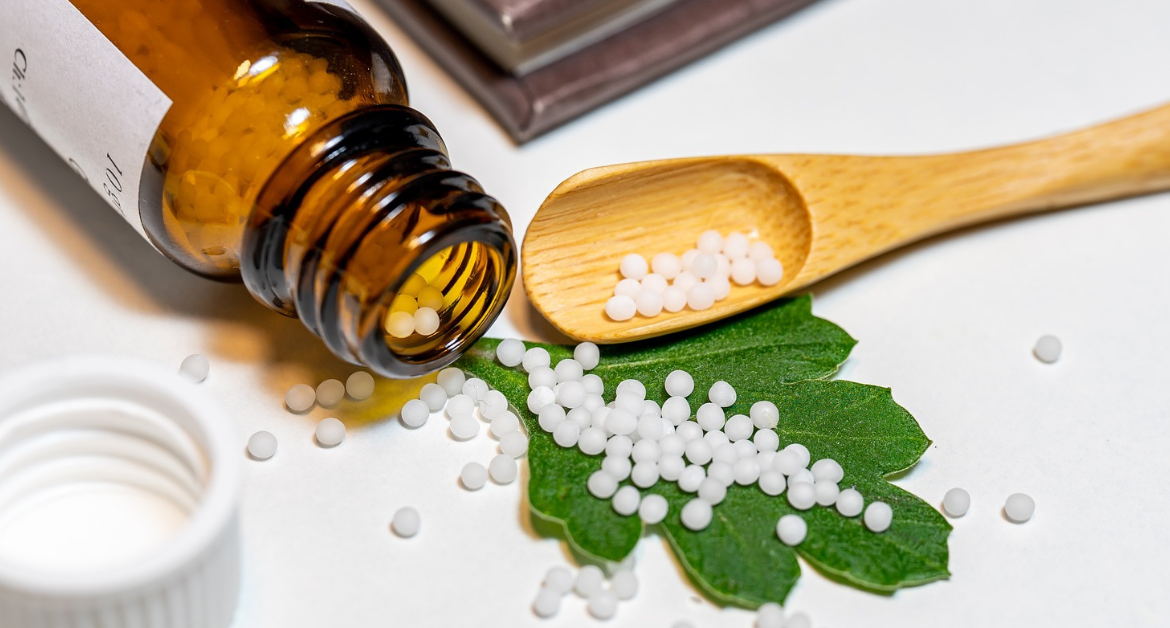 Bottle of homeopathic pills tipped onto a leaf and spoon