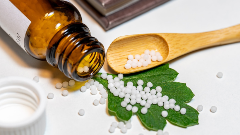 Bottle of homeopathic pills tipped onto a leaf and spoon